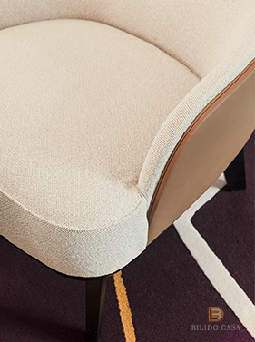 Close-up of a custom beige upholstered chair’s back and armrest, showcasing fabric quality and ergonomic design.